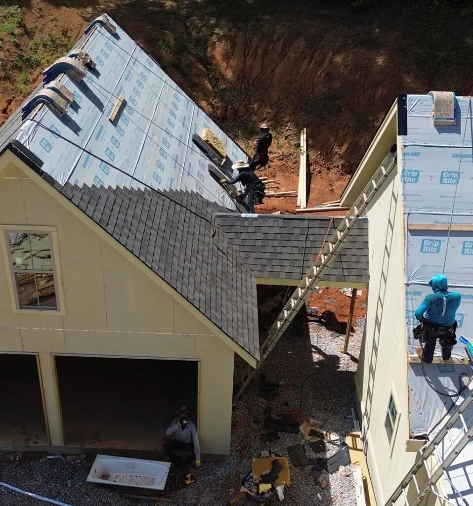 Team of roofers working to replace shingle roof.